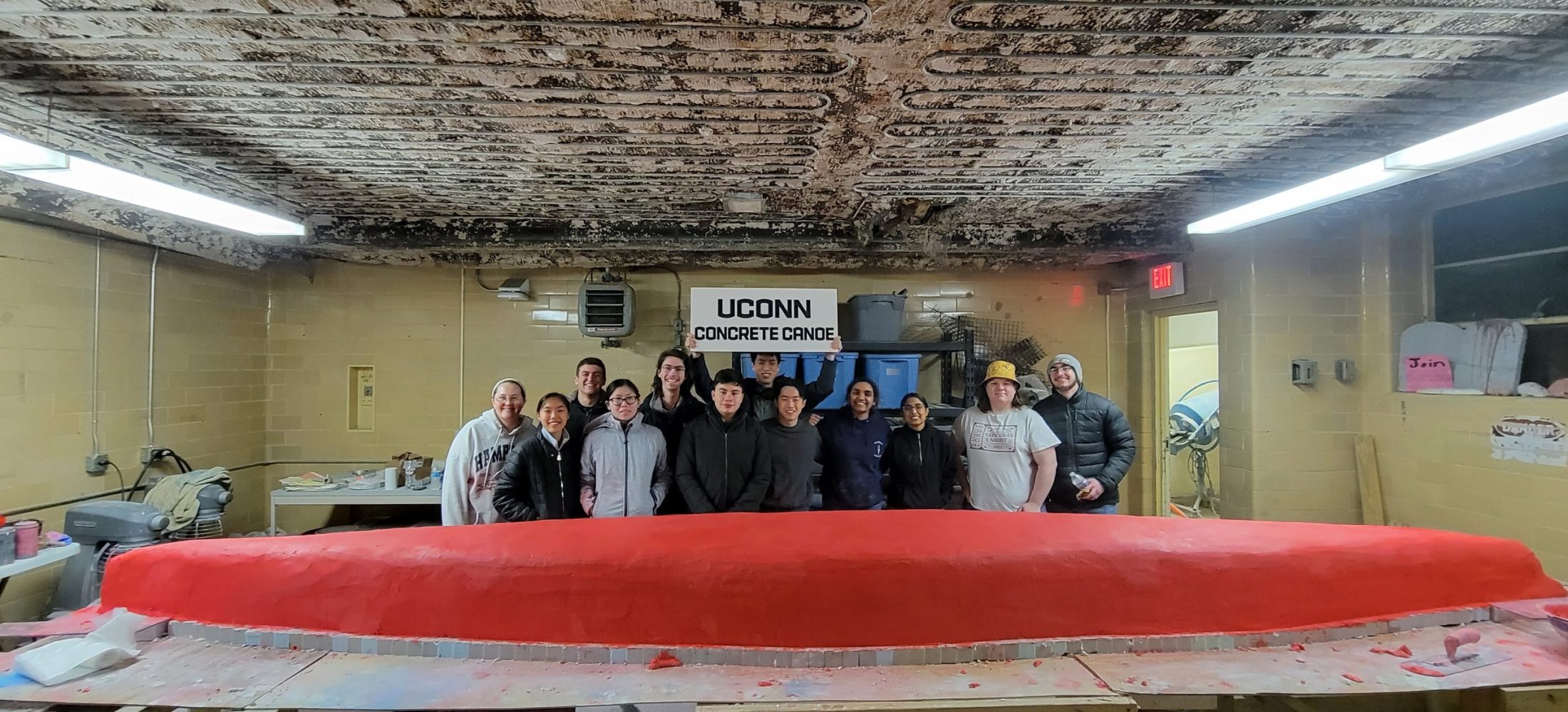 the team proudly standing behind the concrete crustacean canoe after finishing pour day