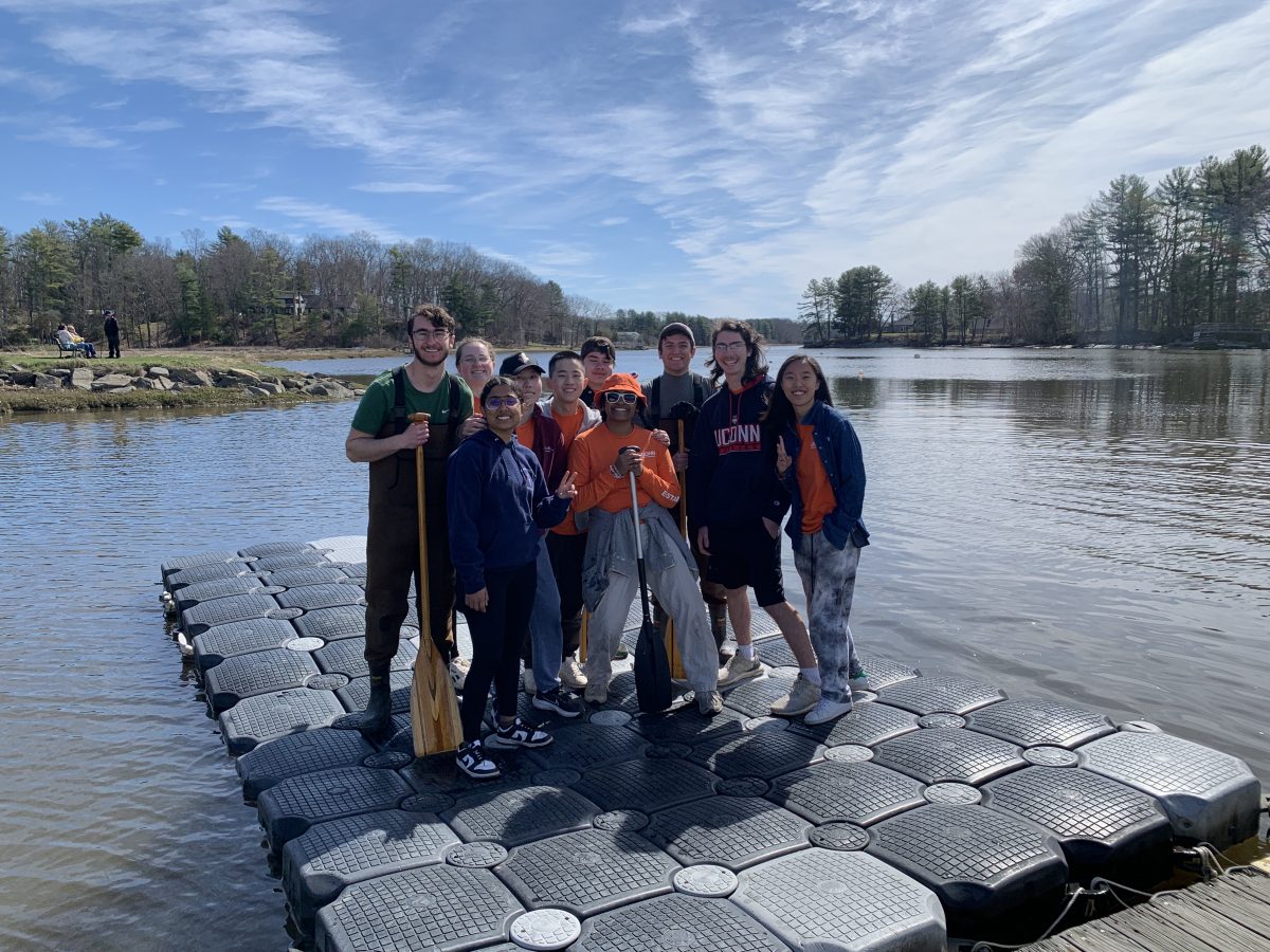 the team gathered together with a lake in background posing with paddles proudly at competition