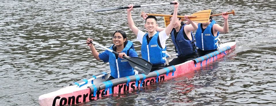 4 members triumphantly returning from a competition race in the red Concrete Crustacean canoe